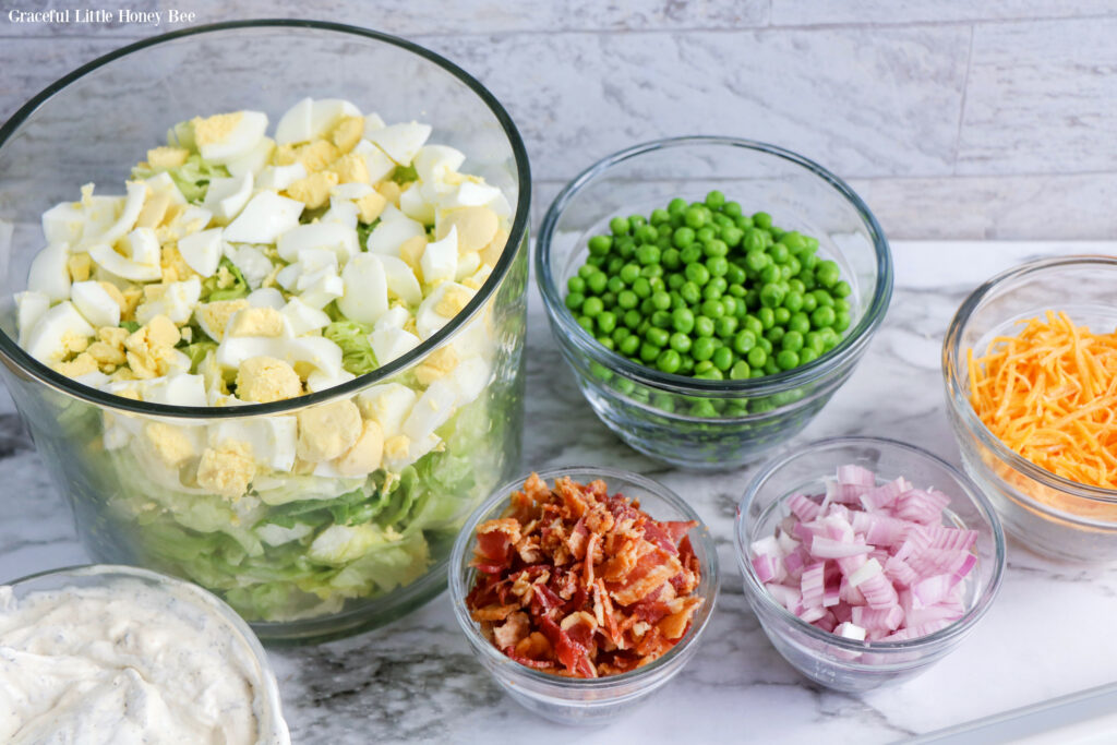 All ingredients chopped and sitting in separate glass bowls sitting on a marble counter.