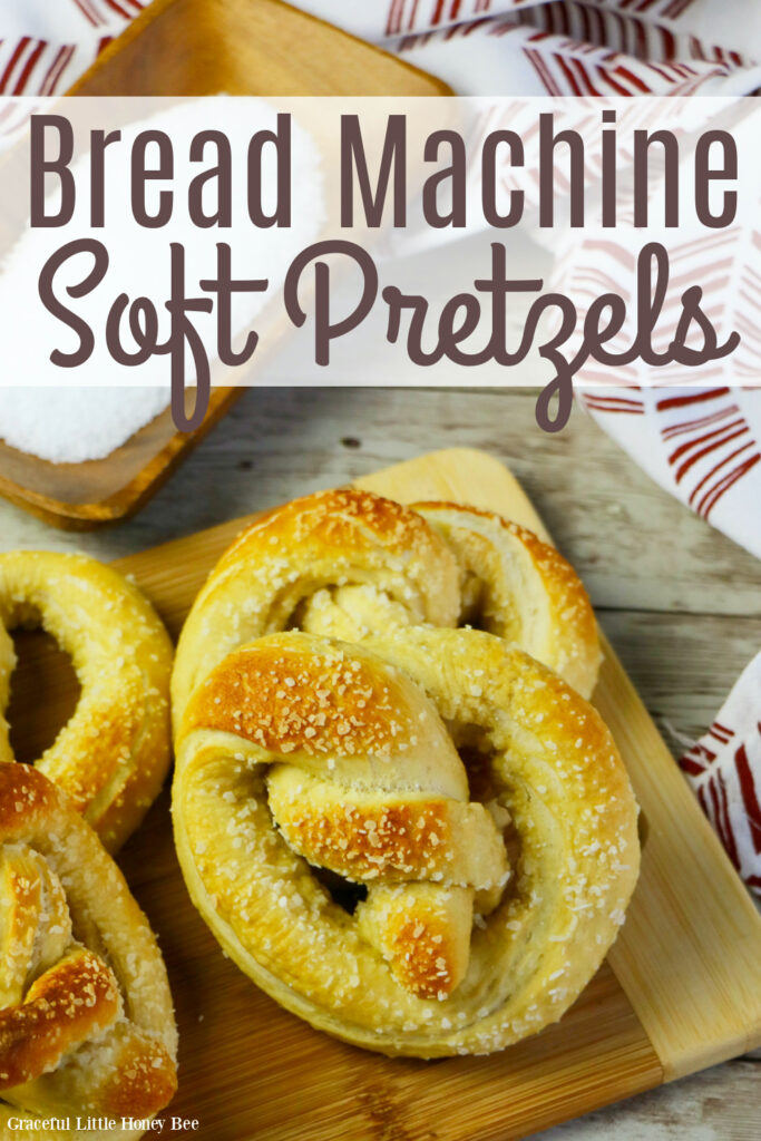 Four soft pretzels sitting on a cutting board.