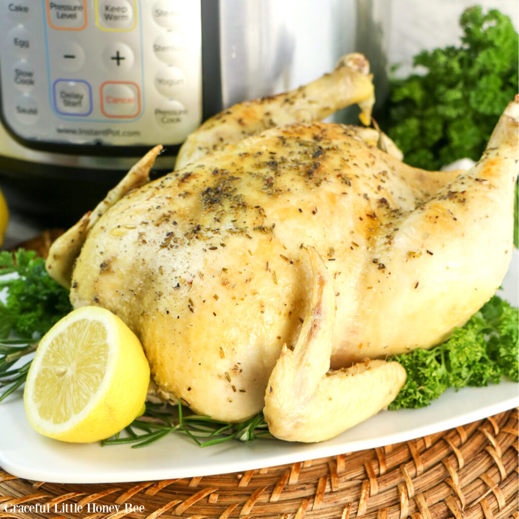 Whole Lemon Garlic Chicken sitting on a white platter garnished with parsley and lemon.