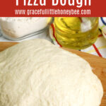 Pizza dough sitting on a wooden cutting board.