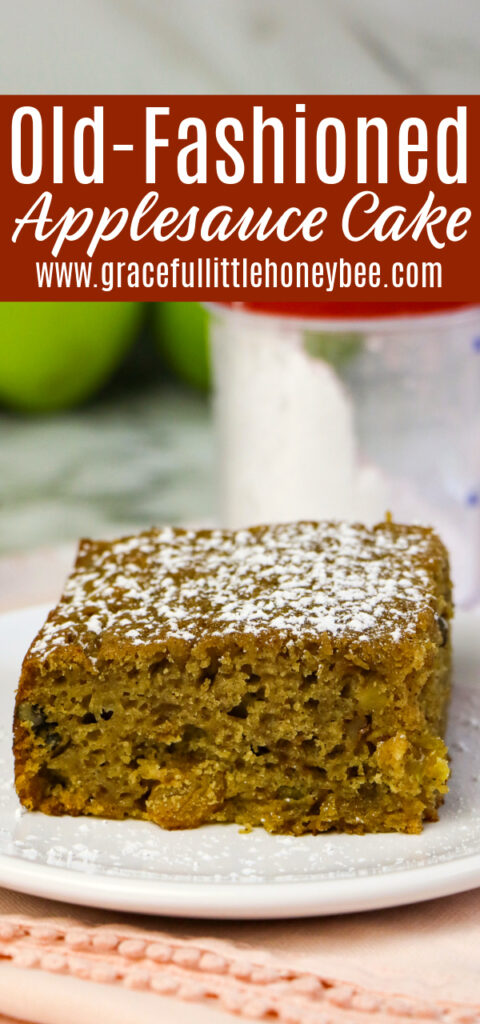 A slice of Applesauce topped with powdered sugar sitting on a white plate with green apples in the background.