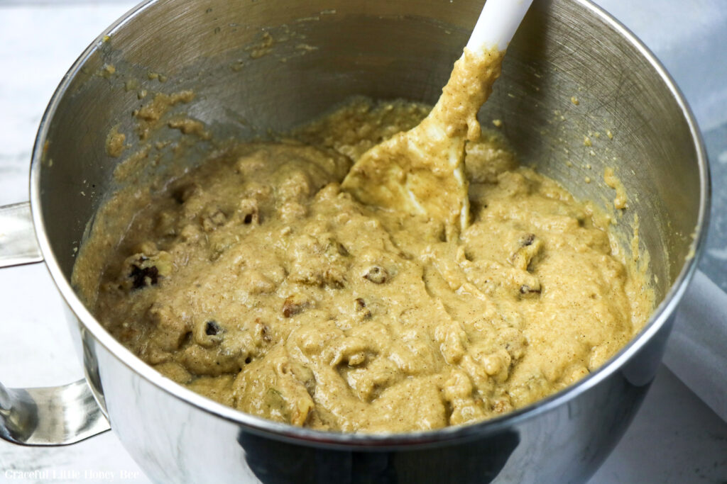 Cake batter in a large silver mixing bowl with a wooden spoon.