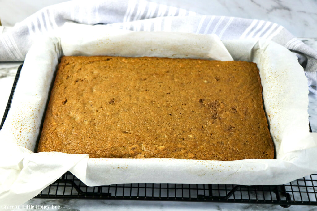 Baked cake sitting in cake pan with parchment paper.