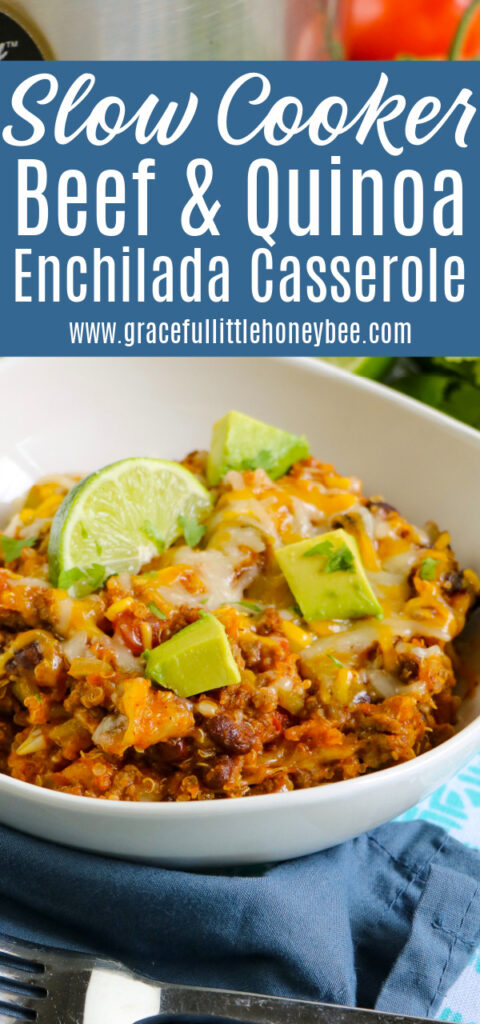 Quinoa Enchilada Casserole in a white bowl topped with cheese and garnished with lime.