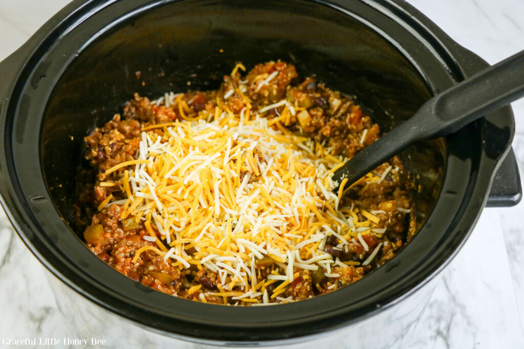 Enchilada casserole with shredded cheese added before mixing it in.