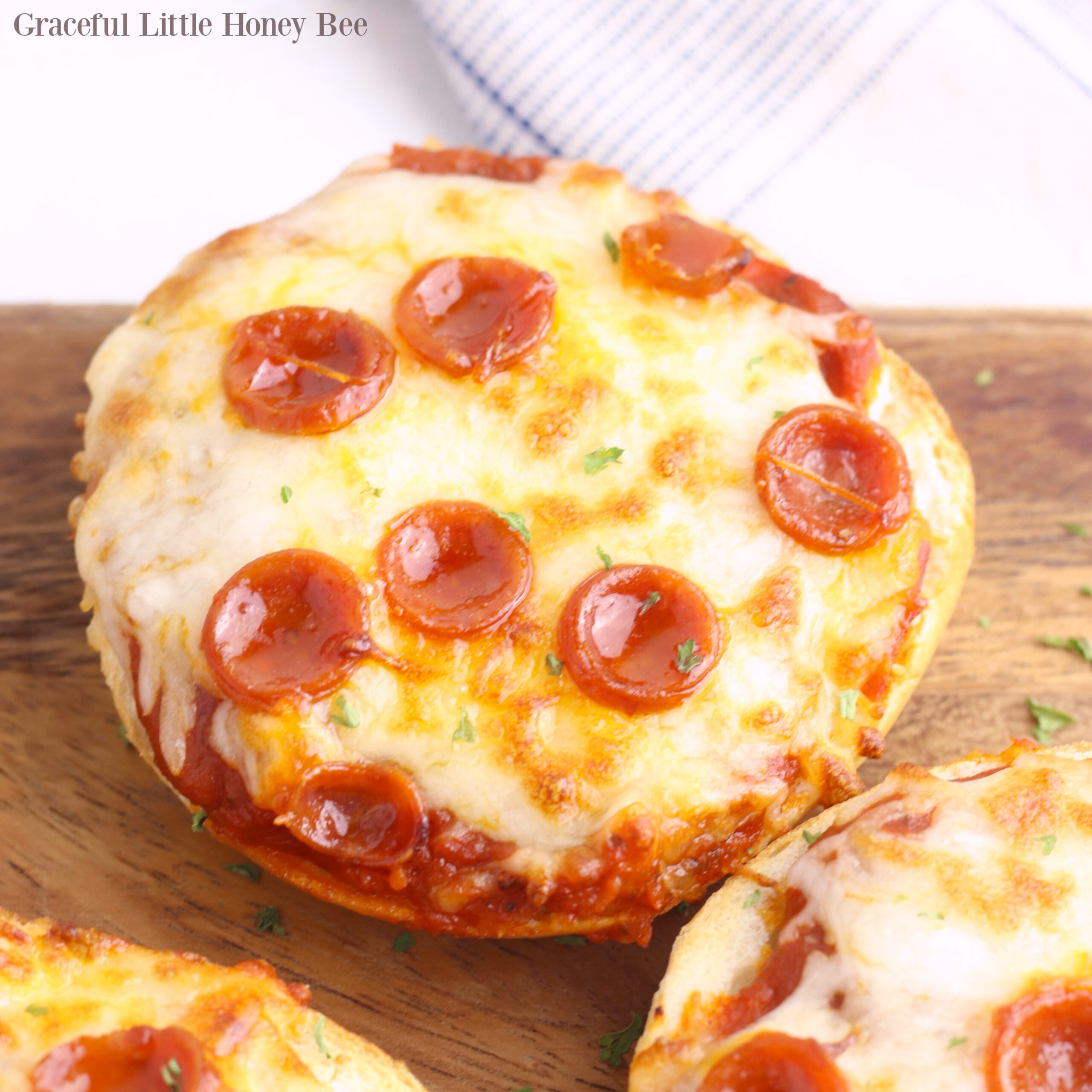 Pizza Bagel sitting on a wooden cutting board.