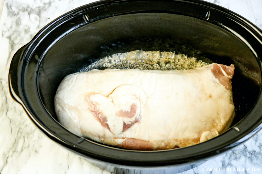 Pork tenderloin and Dr. Pepper in black slow cooker.