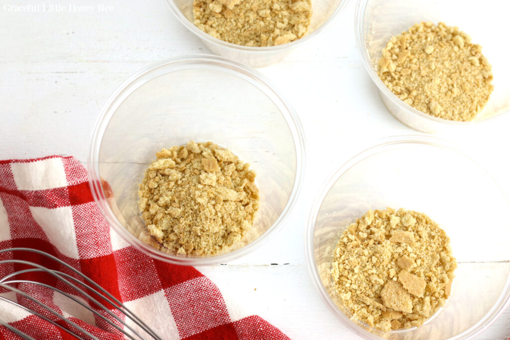 Graham cracker crumbs in clear plastic cups.