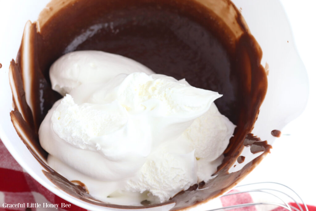 Chocolate pudding and whipped topping in a mixing bowl before being stirred together.