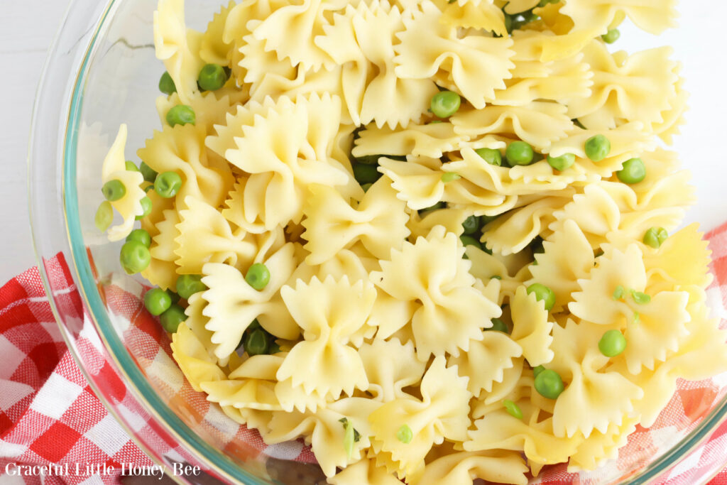 Cooked pasta and peas in a large glass mixing bowl.