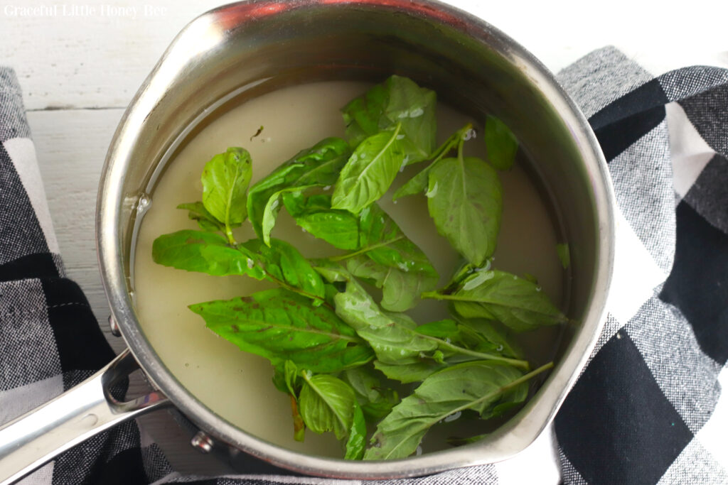 Sugar, water and basil in a saucepan.