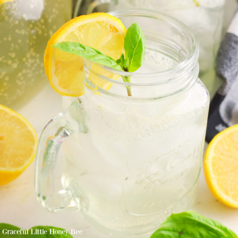 A mason jar full of Basil Sparkling Lemonade garnished with basil and a lemon slice.