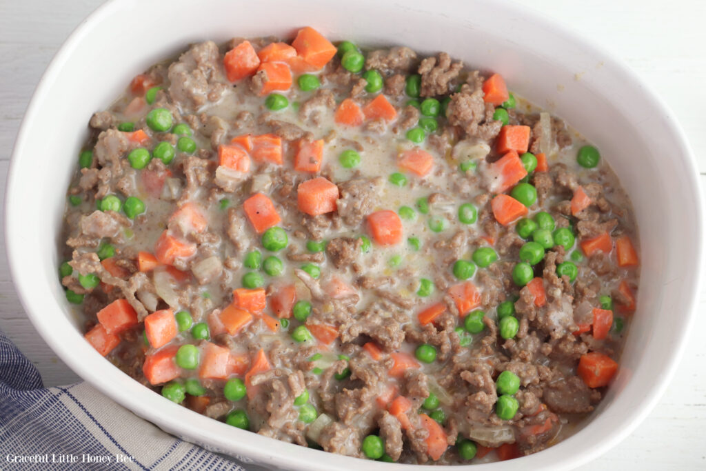 Meat and vegetable mixture in white baking dish.