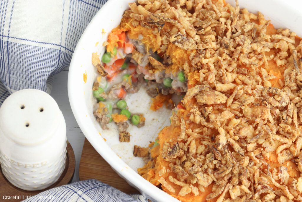 Shepherds Pie in a white baking dish with a serving scooped out.