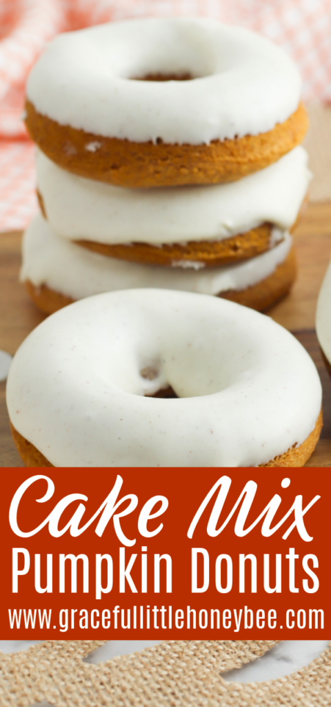 A stack of iced donuts sitting on a wooden cutting board.