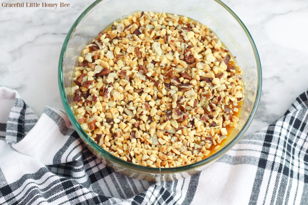 Caramel topped with nuts in a clear glass dish.