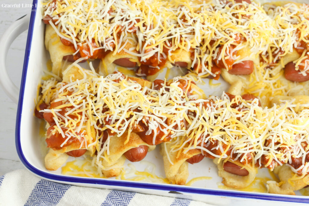 Cooked hot dogs with chili and cheese on top before going back into the oven.