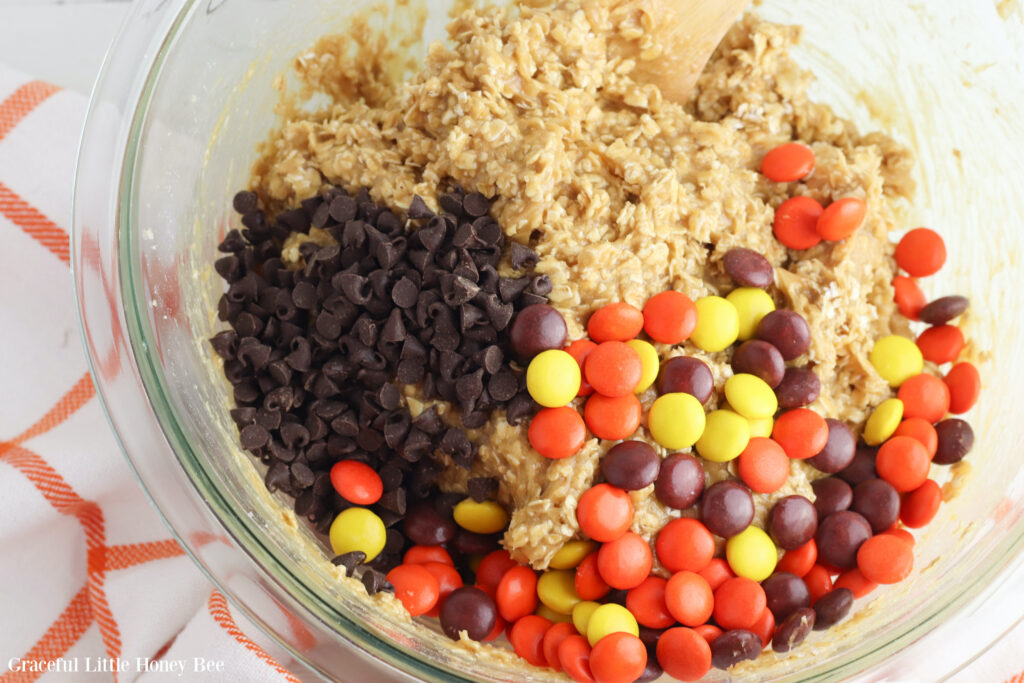 cookie dough with chocolate chips and Reese's Peices sitting on top before being mixed.