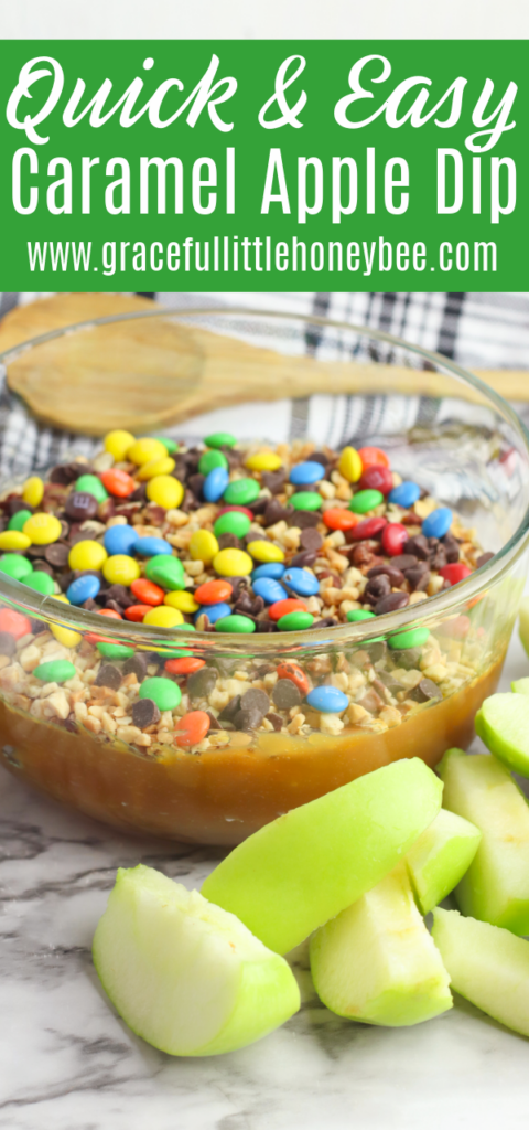 Caramel Apple dip with Peanuts and Chocolate Candy in a clear glass bowl with green apple slices sitting next to it.