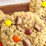 Close up of a Reese's Pieces Monster Cookie sitting on a stack of cookies.