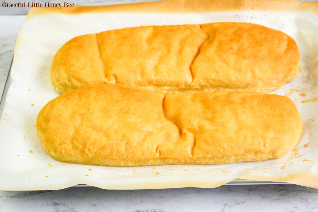 Two loaves of french bread sitting on a baking sheet.