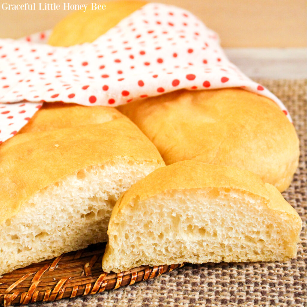 French Bread sitting on a mat with a slice in front and a tea towel laying over the top.