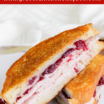 Turkey Cranberry Grilled Cheese sliced in half and laying on a white plate.