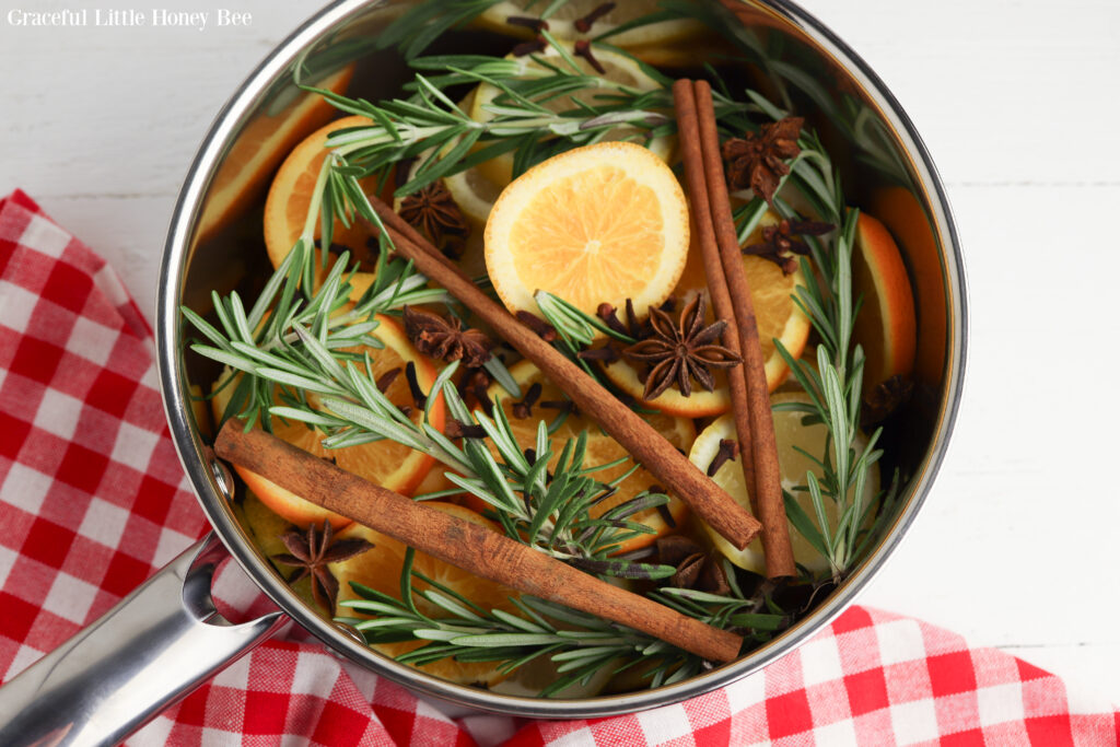 Fresh citrus slices, rosemary, cinnamon sticks and star anise in a stockpot.