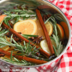 Fresh citrus slices, rosemary and cinnamon sticks in a stockpot full of water.