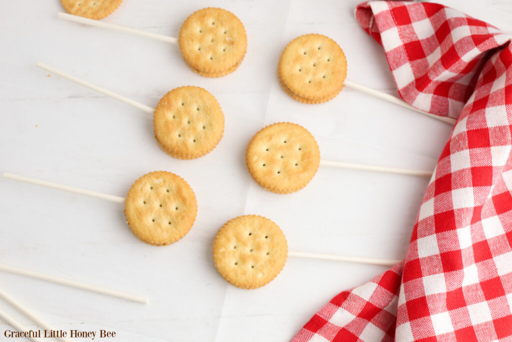 Peanut butter and a sucker stick sandwiched between two Ritz Crackers.