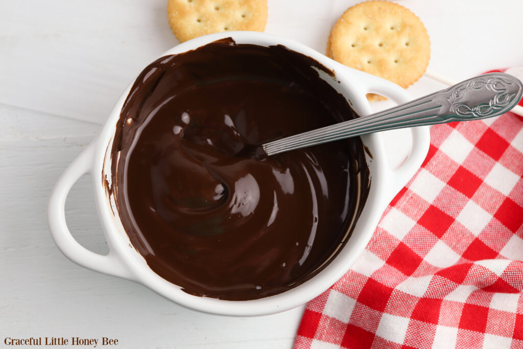 Melted chocolate in a small bowl with a spoon sitting in it.