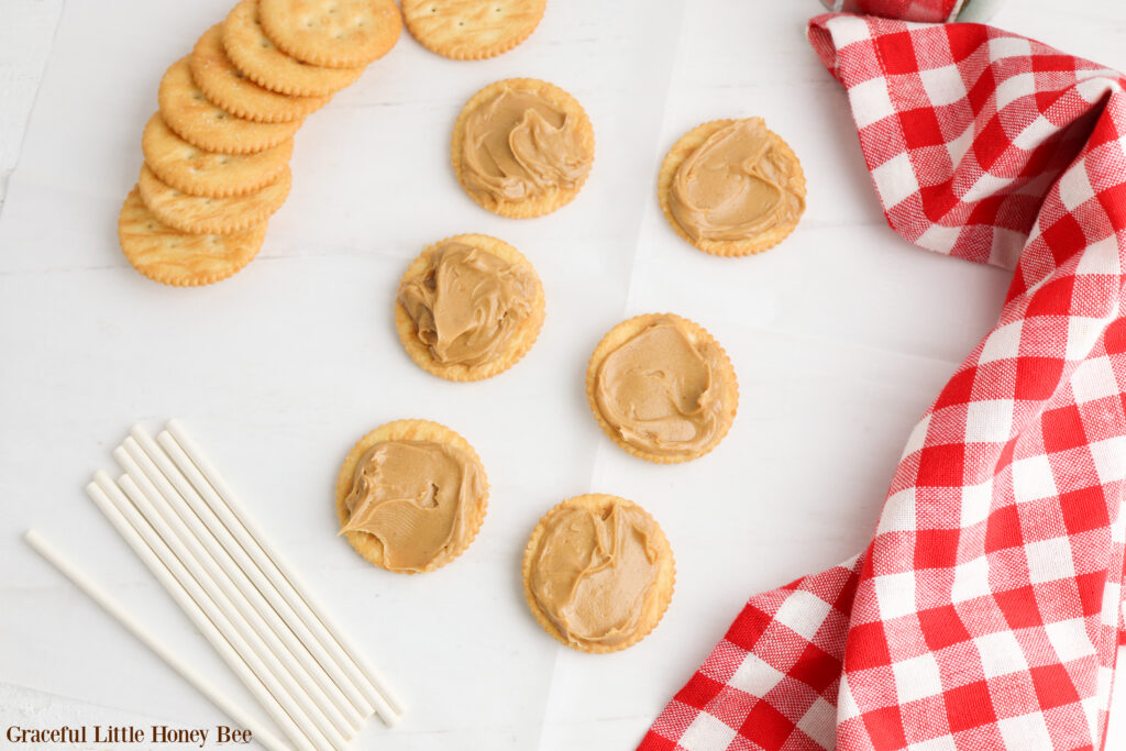 Ritz crackers with a layer of peanut butter on them sitting in a row.