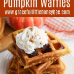 A stack of pumpkin waffles with whipped cream on top.