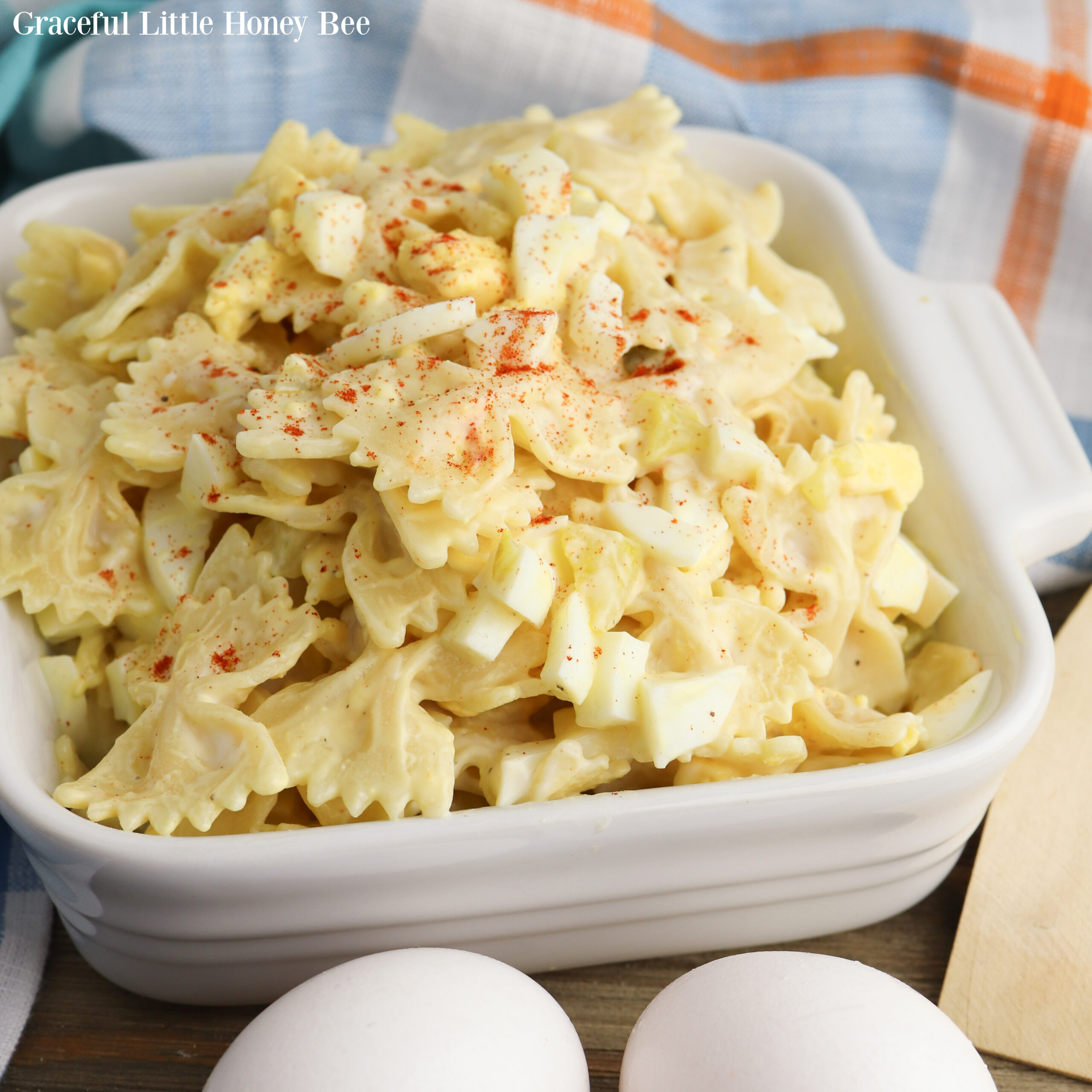 Plated pasta salad in a white square serving dish topped with paprika for garnish.