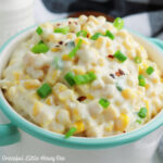 A bowl of cream cheese corn topped with green onion.