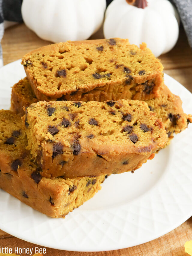 Pumpkin bread sliced and stacked on a white plate.