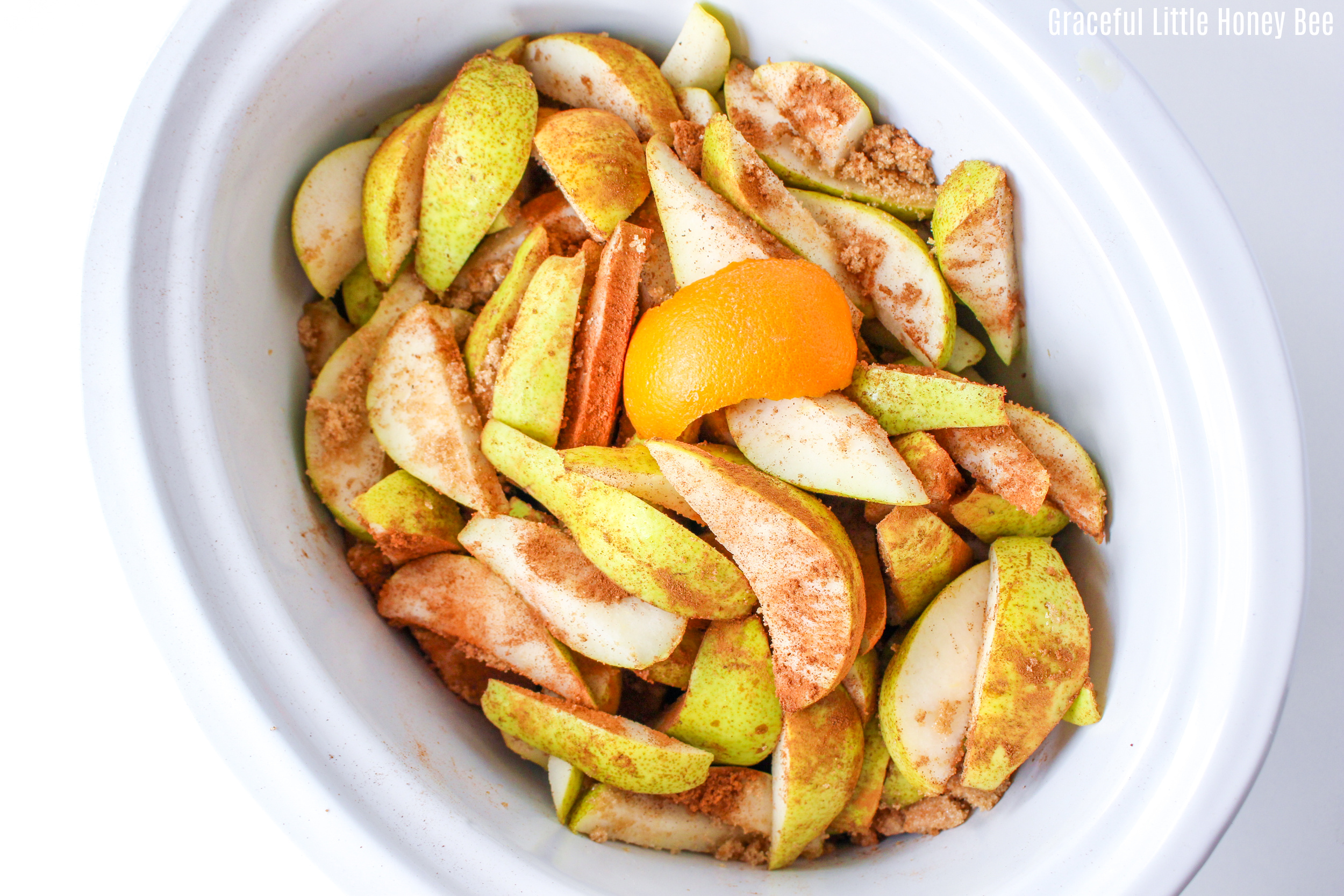 Sliced pears spinkled with spices in a white slow cooker.