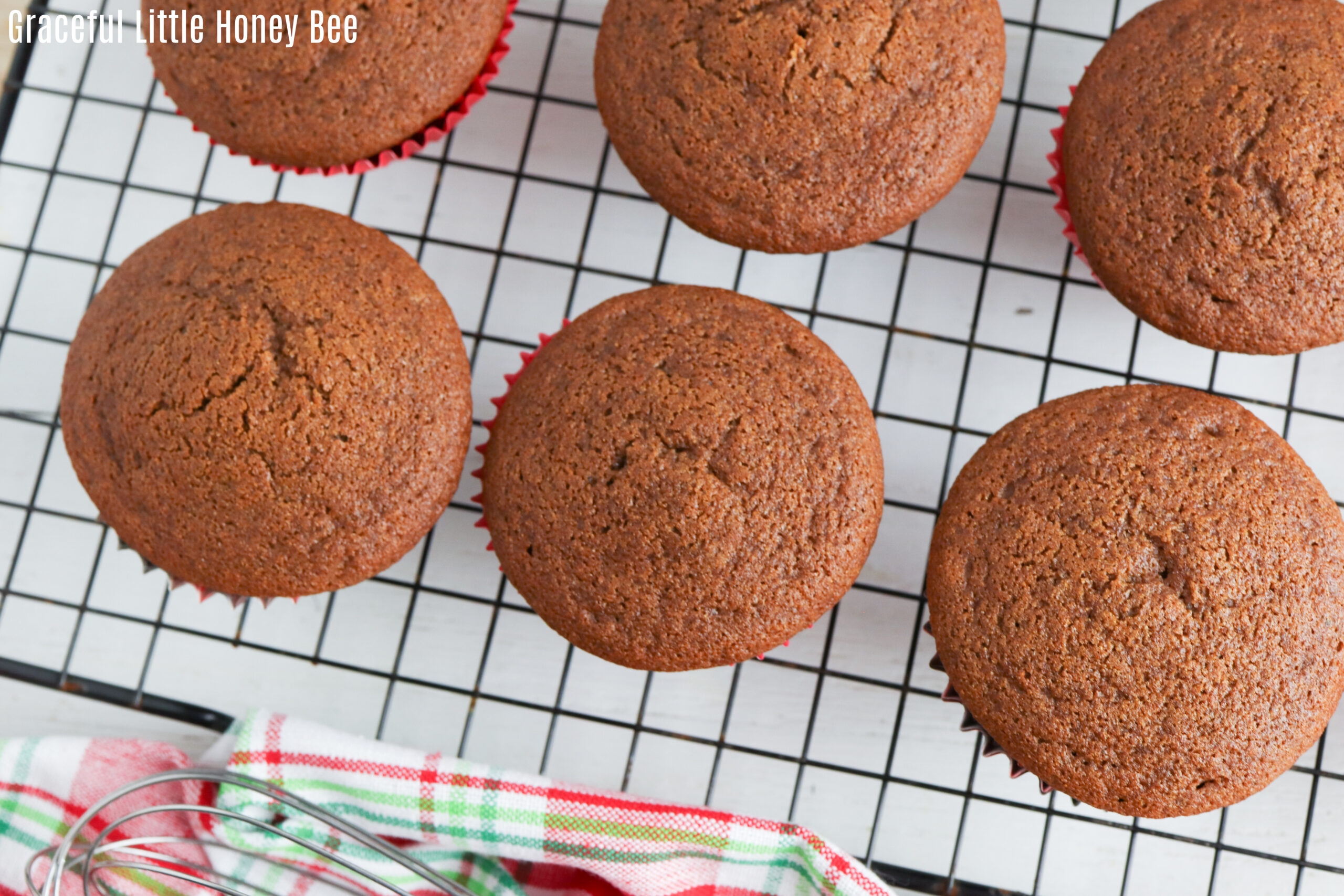 Gingerbread muffins sitting on a black wire cooling rack.