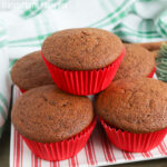 Close up of gingerbread muffins stacked on a red and white striped plate in red cupcake liners.