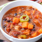 Sweet Potato Chicken Chili in a white bowl, garnished with sliced jalapeno.