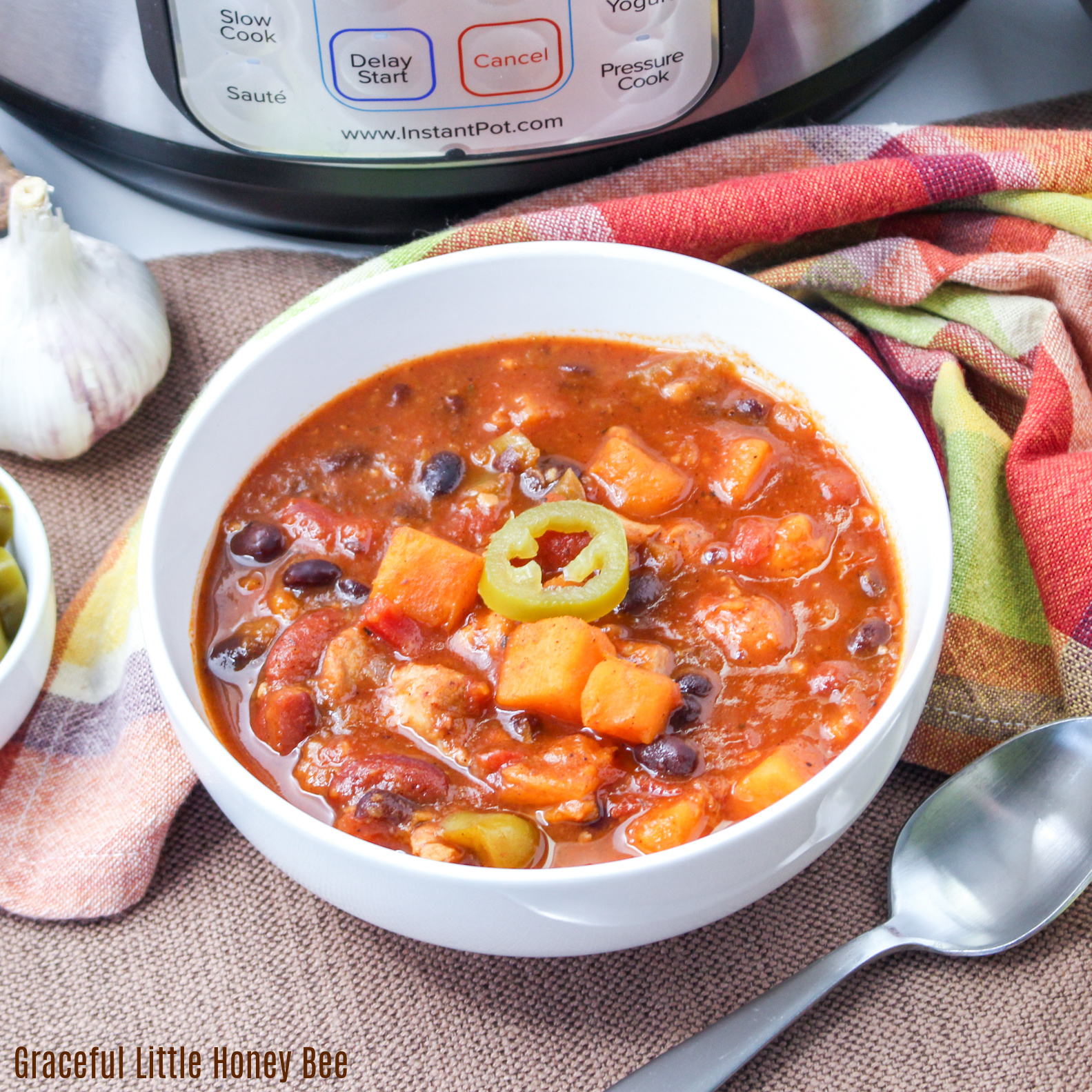 Sweet Potato Chicken Chili in a white bowl, garnished with sliced jalapeno.