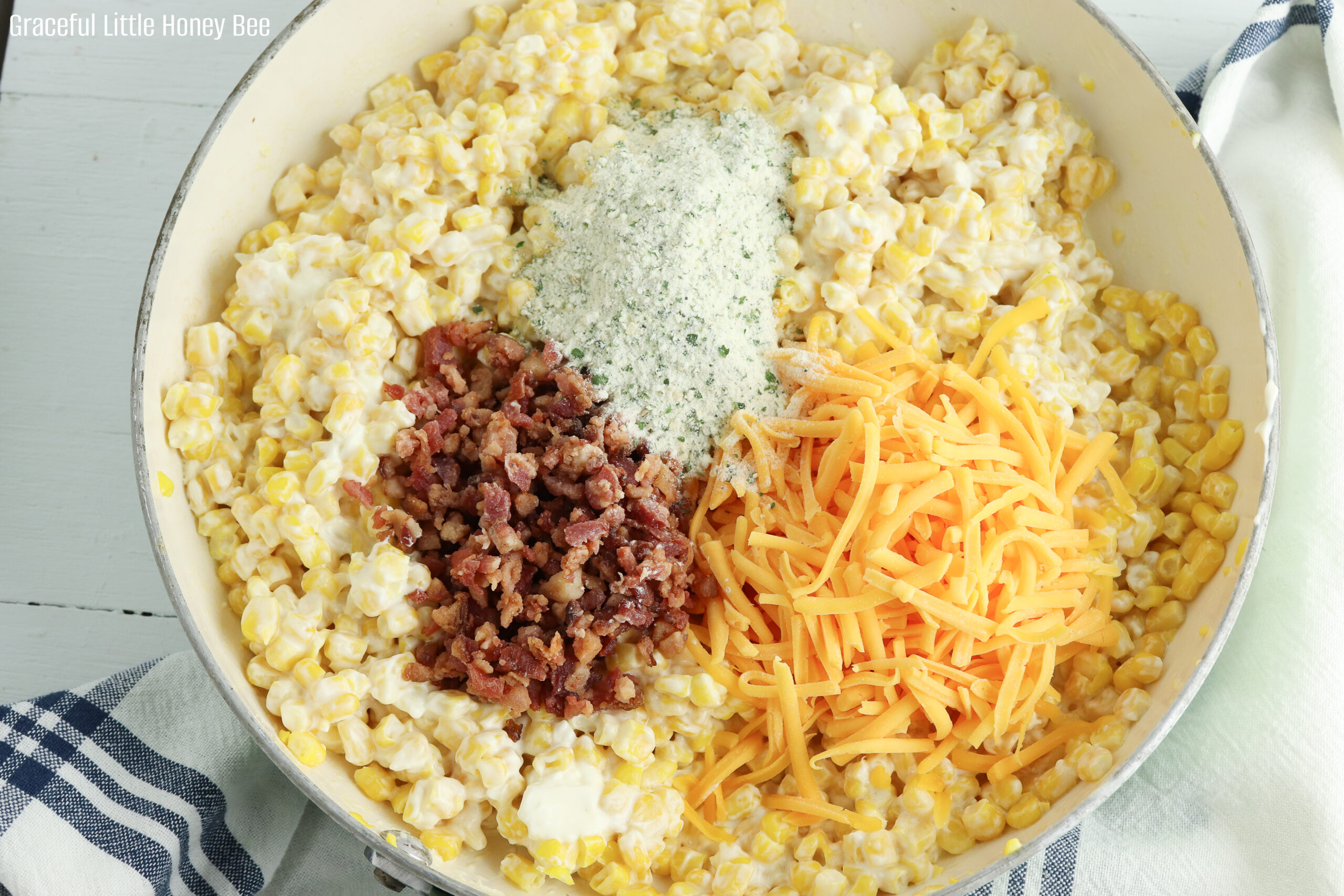 Cream cheese corn with shredded cheese, crumbled bacon and ranch seasoning on top before being stirred together.