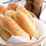 Breadsticks sitting on a basket lined with a white napkin.