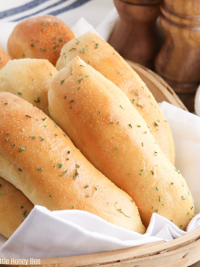 Breadsticks sitting on a basket lined with a white napkin.