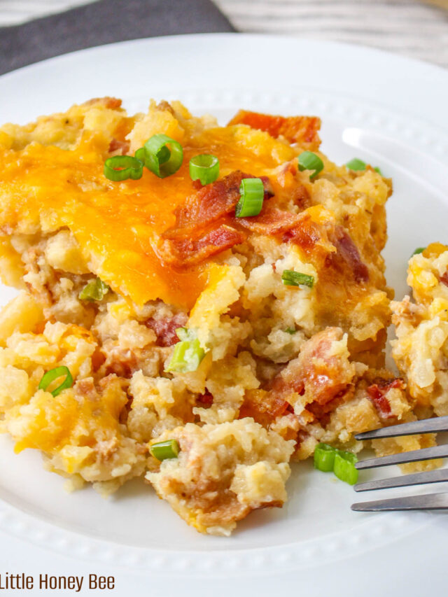 A serving of Loaded Baked Potato Casserole sitting on a round white plate with a fork.