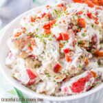 A close up view of Bacon Ranch Potato Salad in a round white bowl.