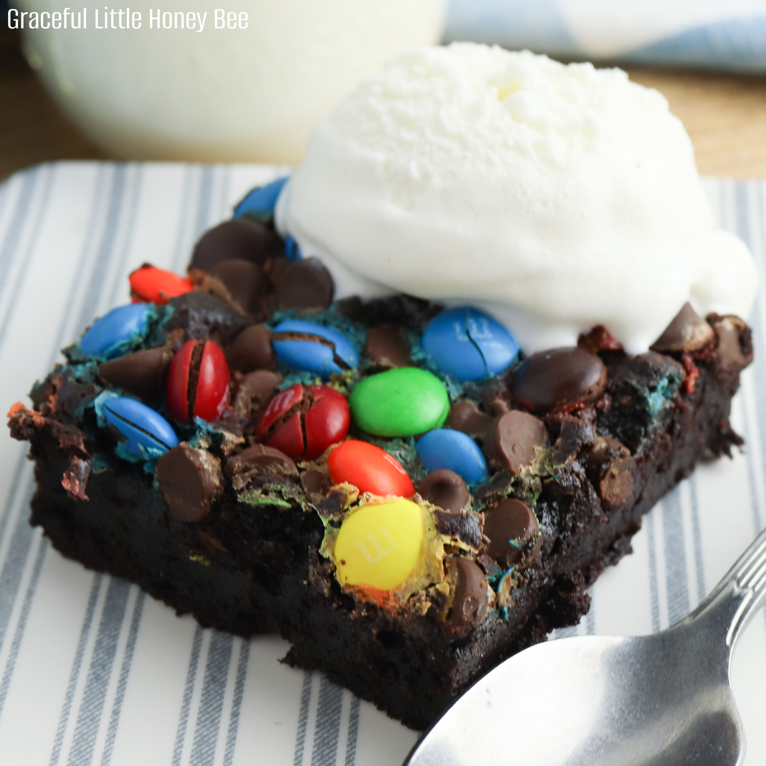 A serving of chocolate dump cake sitting on a blue and white striped plastic plate with a scoop of vanilla ice cream on top.