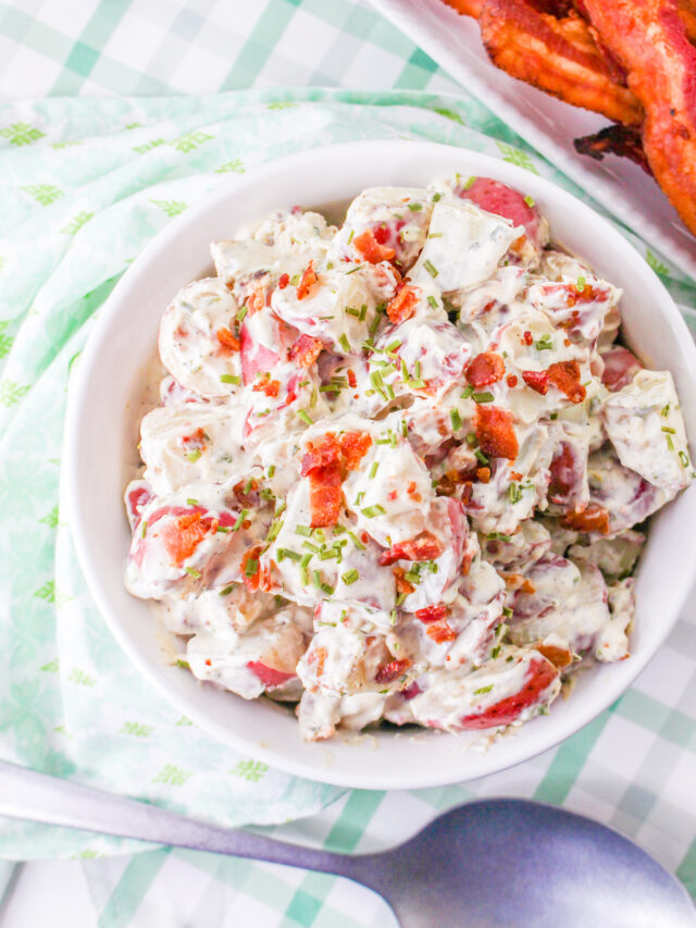 A close up view of Bacon Ranch Potato Salad in a round white bowl.
