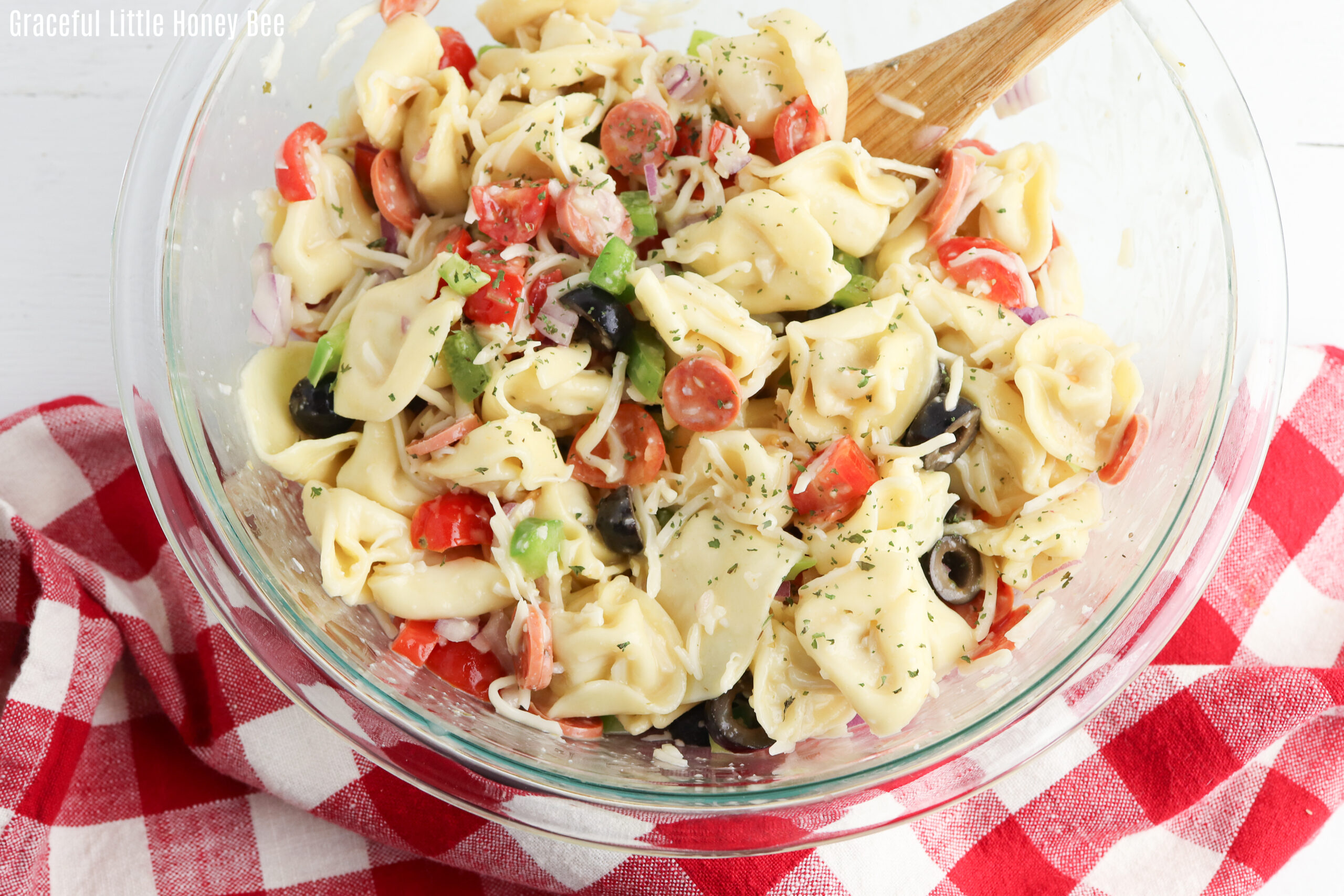 Tortellini Pasta Salad in a clear glass mixing bowl.