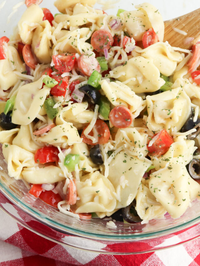 Tortellini Pasta Salad in a clear glass mixing bowl.